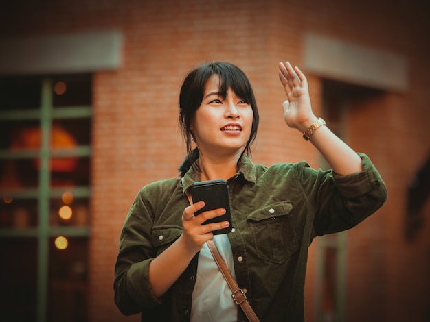 Mulher asiática usando smartphone com bom humor em shopping center