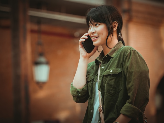 Mulher asiática usando smartphone com bom humor em shopping center