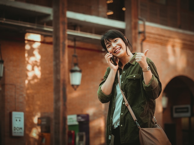 Mulher asiática usando smartphone com bom humor em shopping center