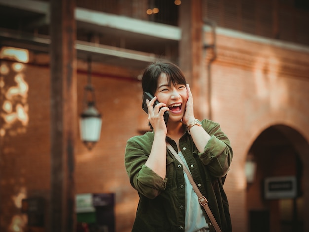 Mulher asiática usando smartphone com bom humor em shopping center