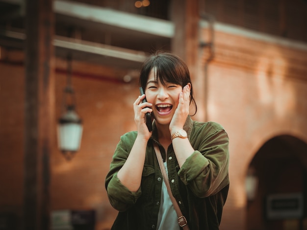 Mulher asiática usando smartphone com bom humor em shopping center