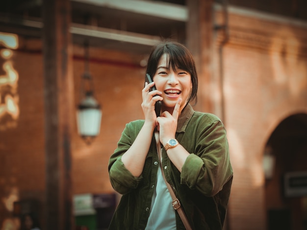 Mulher asiática usando smartphone com bom humor em shopping center