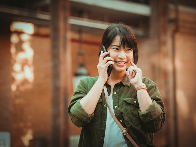 Mulher asiática usando smartphone com bom humor em shopping center