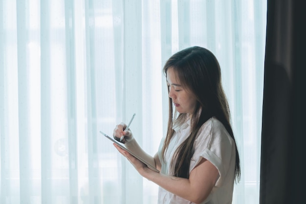 Mulher asiática usando tablet pc na sala de estar em casa conceito de negócio
