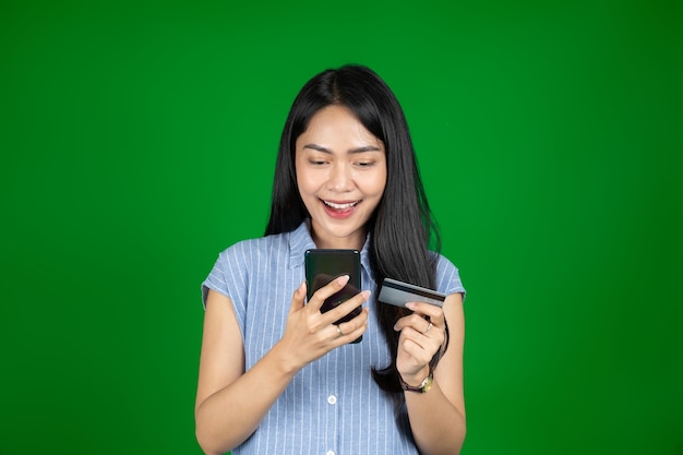 Mulher asiática usando telefone celular enquanto segura o cartão atm