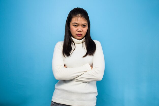 Mulher asiática usando uma camiseta branca com fundo azul isolado Dobre as mãos e gesto irritado