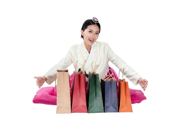Mulher asiática vestindo um traje tradicional coreano Hanbok sentado e mostrando sacolas de compras