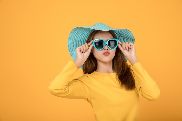 Mulher asiática vestir conceito Férias com uma camisa amarela Óculos de sol e chapéus são azuis e fazem rostos muito felizes.