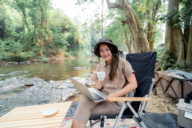 Mulher asiática viaja e acampa sozinha. empresária online trabalhando e relaxando durante a atividade ao ar livre da viagem.