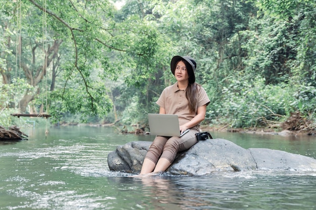 Mulher asiática viaja e acampa sozinha. Empresária online trabalhando e relaxando durante a atividade ao ar livre da viagem.