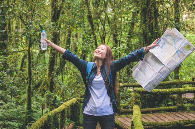 Foto mulher asiática viajante com mochila sorrindo e segurando o mapa com garrafa de água