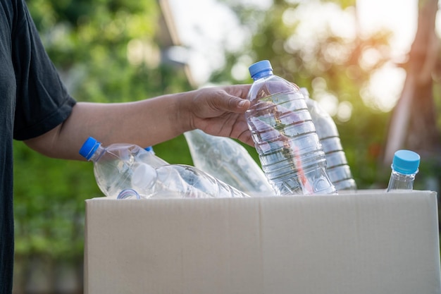 Mulher asiática voluntária carrega garrafas plásticas de água no lixo da caixa de lixo no parque recicla o conceito de ecologia do ambiente de resíduos