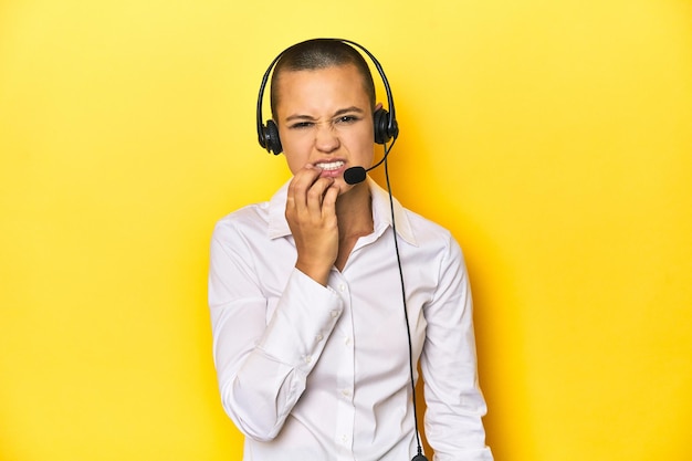 Mulher assistente virtual com fone de ouvido fundo amarelo roer unhas nervosas e muito ansiosas