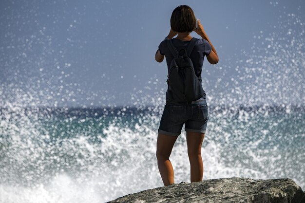 Mulher assistindo tempestade de tempestade do mar na costa