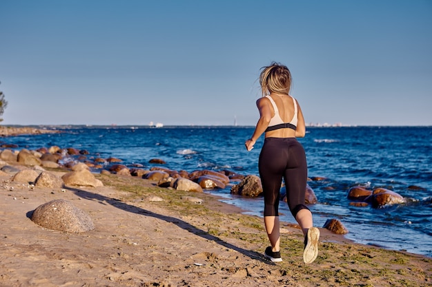 Mulher ativa corre perto da costa no dia de verão