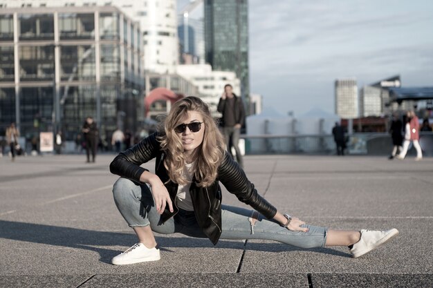 Mulher atleta ou dançarina fendeu a perna em paris, França. Mulher sensual com cabelo comprido em jeans e óculos de sol, moda. Ioga, pilates, dança, desporto. Moda, beleza, aparência. Férias, viagens, desejo de viajar.