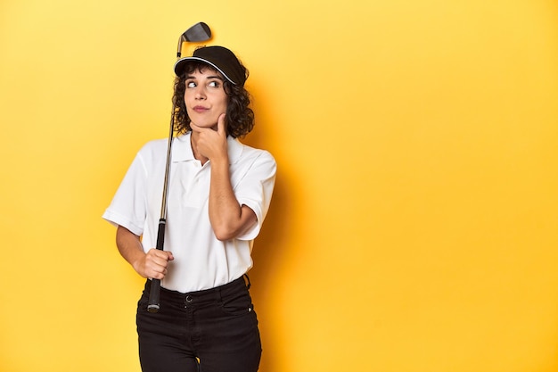 Foto mulher atlética caucasiana com cabelo encaracolado jogando golfe no estúdio olhando de lado