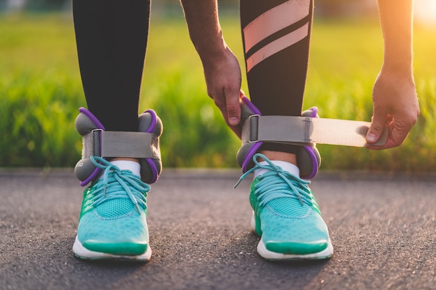 Mulher atlética coloca pesos de esportes para caminhar durante o treino ao ar livre. Estilo de vida saudável e esportivo.