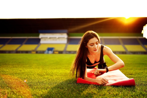 Mulher atlética forte malhando no estádio faz uma prancha lateral vestindo roupas esportivas confortáveis