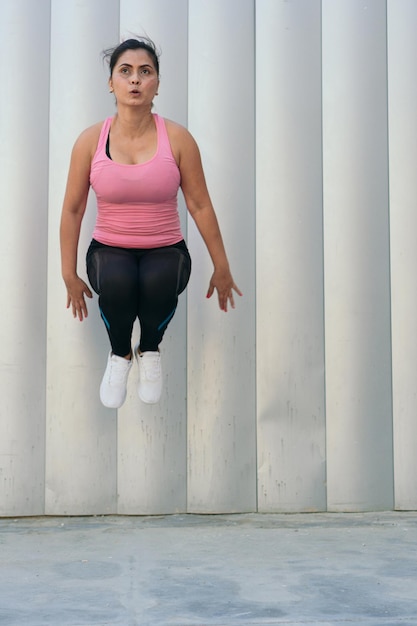 Mulher atlética pulando durante um treino ao ar livre