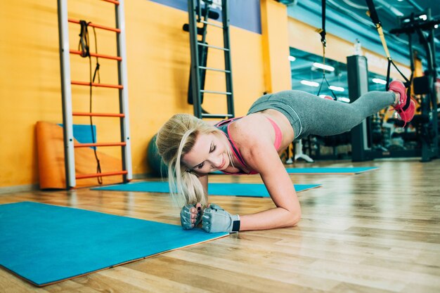 Mulher atlética treinando trx na academia