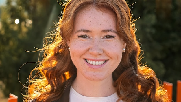 Mulher atraente com cabelo encaracolado sorrindo para a câmera na rua