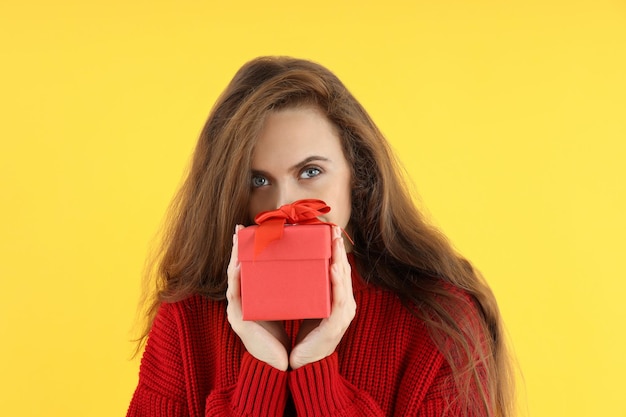 Mulher atraente com caixa de presente em fundo amarelo