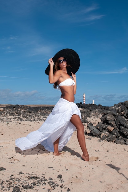 mulher atraente com chapéu em uma área costeira e praia com bom tempo