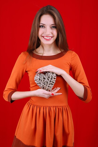 Mulher atraente com coração de vime, sobre fundo vermelho