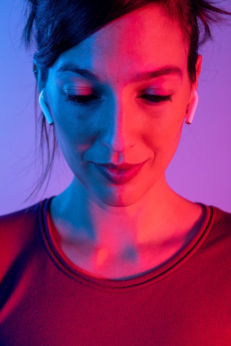 Foto mulher atraente com fones de ouvido ouvindo música no estúdio com luzes azuis e vermelhas