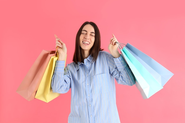 Mulher atraente com sacolas de compras em fundo rosa