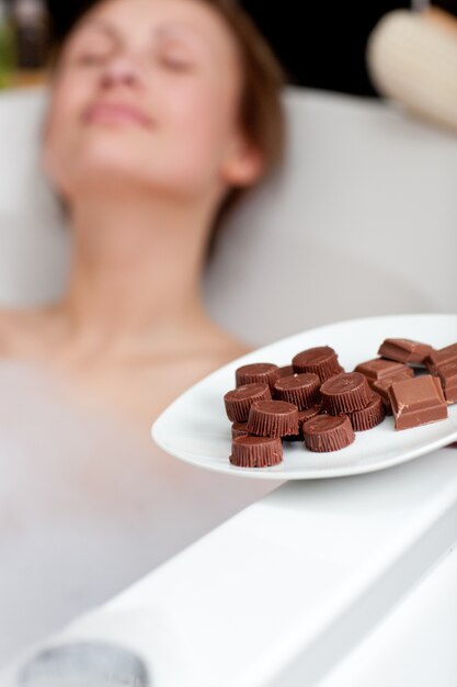 Mulher atraente comendo chocolate ao tomar banho