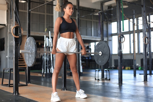 Mulher atraente de ajuste muscular exercitando os músculos do edifício.