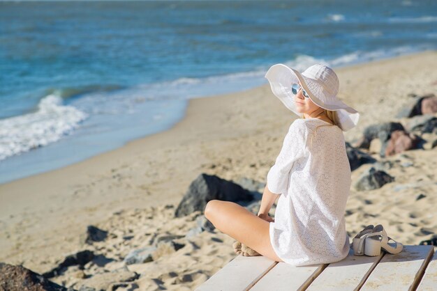 Mulher atraente de chapéu grande relaxante na costa do oceano ou mar