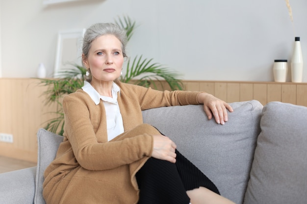 Mulher atraente de meia idade relaxando no sofá em casa.