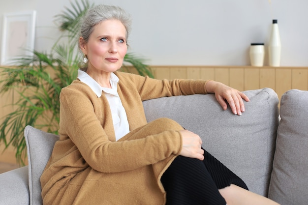 Mulher atraente de meia idade relaxando no sofá em casa.