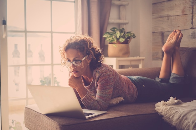 Mulher atraente de meia-idade usando tecnologia de laptop de internet em casa