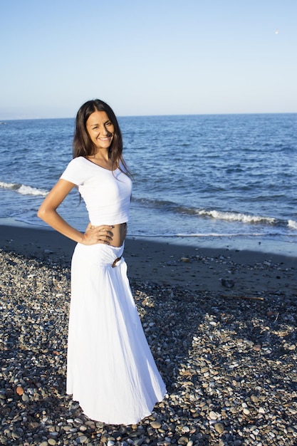 Foto mulher atraente de vestido branco na praia expressão positiva