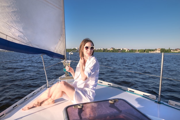 Mulher atraente, descansando em um navio com um copo de vinho