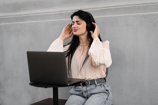 Mulher atraente dj com laptop e fones de ouvido misturando música e ouvindo nova composição Adorável garota georgiana aproveite sua vida ouvindo música e conversando com amigos