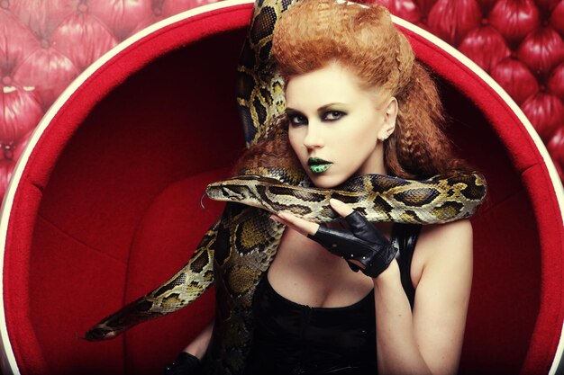 Mulher atraente em cadeira vermelha holdung python