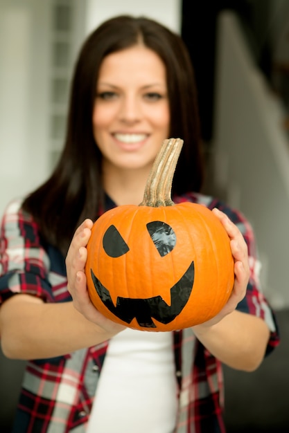 Mulher atraente em casa com uma abóbora de halloween