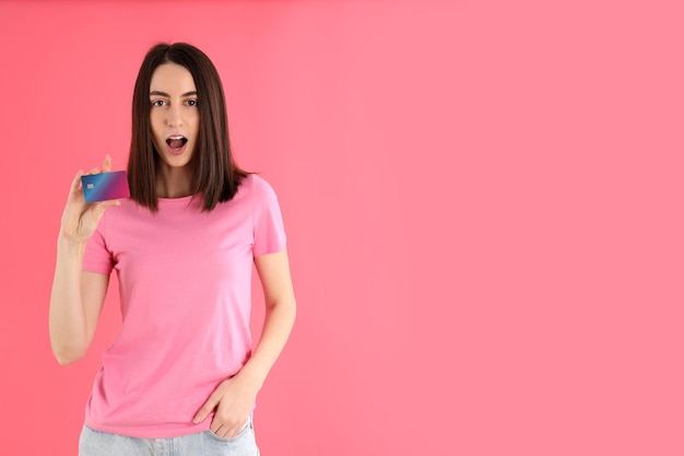 Mulher atraente em t-shirt detém cartão em fundo rosa