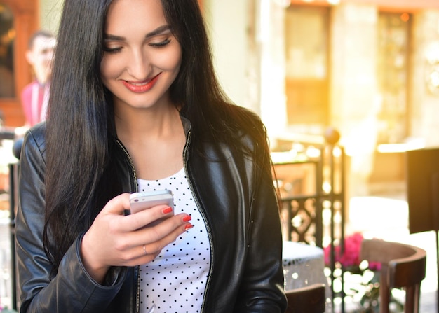 Mulher atraente em um café de rua com um telefone