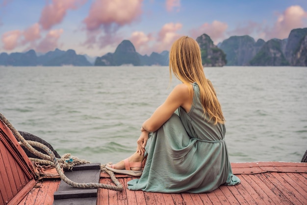 Mulher atraente em um vestido está viajando de barco na baía de halong vietnã viagem à ásia felicidade emoção conceito de férias de verão paisagem marinha pitoresca baía de ha long vietnã