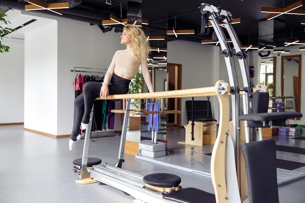 Mulher atraente fitness em roupas esportivas olhando para longe enquanto posava no estúdio de pilates tendo treino dentro de casa Conceito de alongamento de estilo de vida ativo esportivo