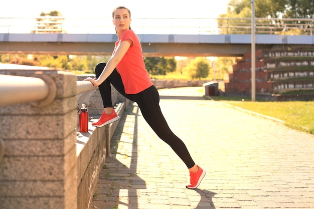 Mulher atraente jovem fitness vestindo roupas esportivas, exercícios ao ar livre, exercícios de alongamento.