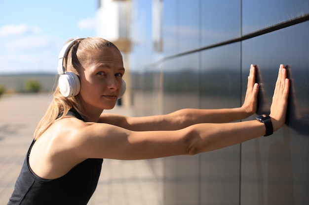 Mulher atraente jovem fitness vestindo roupas esportivas, exercícios ao ar livre, exercícios de alongamento.