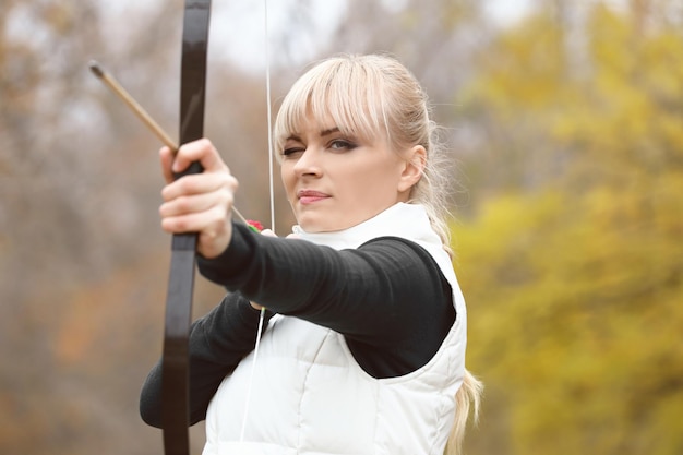 Mulher atraente praticando tiro com arco ao ar livre