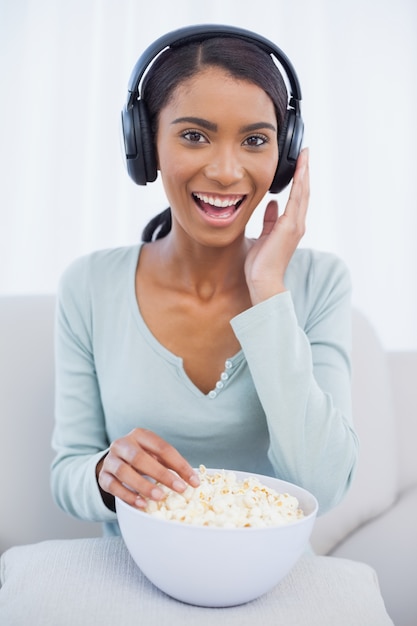 Mulher atraente que come pipoca enquanto ouve música